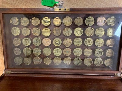 Lot 467 - WOODEN DISPLAY BOX OF BRASS PETROL CAN CAPS